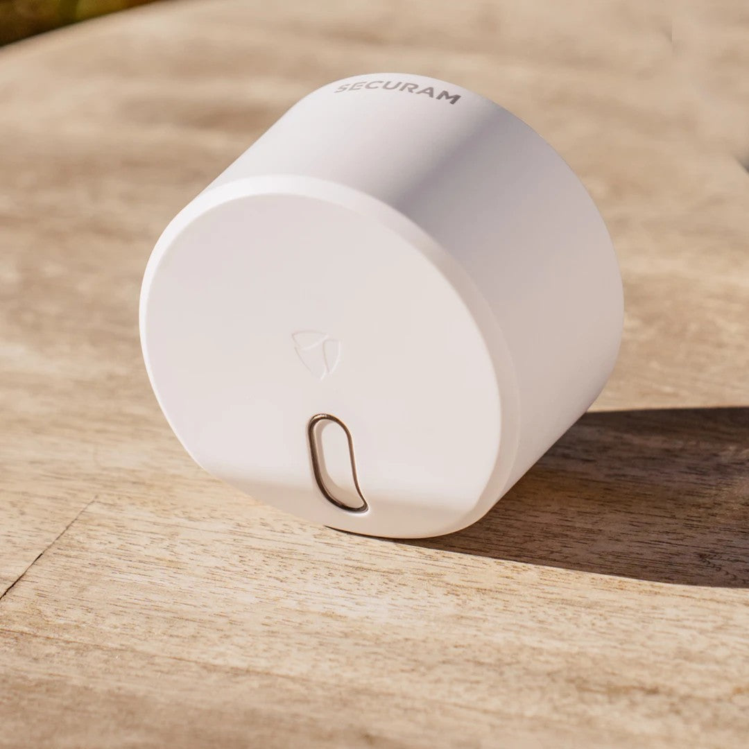 A small white SECURAM Smart Home Security Kit - EOS Wi-Fi Smart Lock, Smart Hub, and Smart Door/Window Sensors sitting on top of a wooden table.